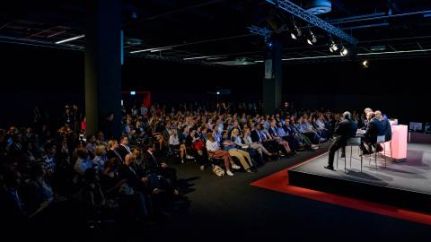Menschenmenge im halbdunklen raum, helle bühne