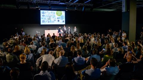 Menschenmenge im halbdunklen raum, helle bühne